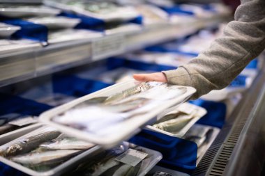 Çocukların elleri süpermarkette balık seçiyor.