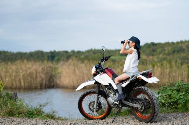 Kız off-road bisikleti sürüyor ve uzaktan dürbünle bakıyor.