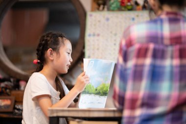 Evde annesiyle ders çalışan bir kız.