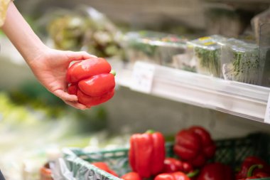 Kadın eli süpermarkette kırmızı biber seçiyor. 