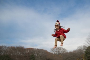 Küçük bir kız parkta zıplıyor..