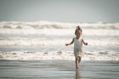 Kumsalda koşan küçük kız.