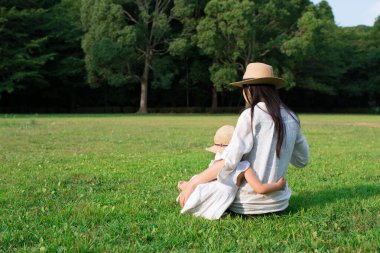 Anne ve kızı çimenlerde oynuyorlar.