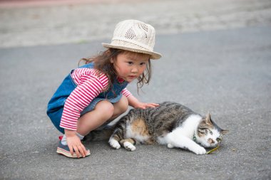 Kız ve kedi dışarıda oynuyorlar.