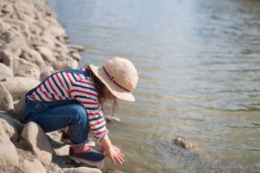 Güzel küçük Asyalı kız nehirde oynuyor.
