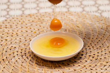 Çiğ yumurtalar küçük beyaz bir tabağa düşüyor.