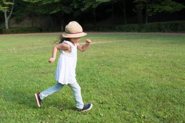 Küçük kız yazın çimenlerde oynuyor..