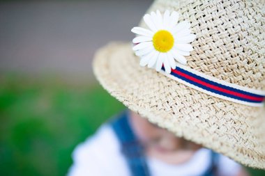 Dışarıda çiçekli şapkalı bir çocuk. 