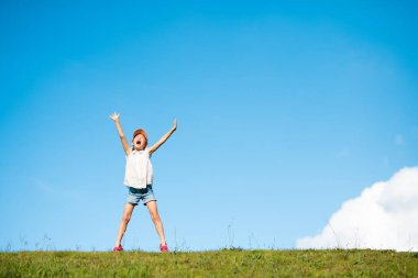 Çocuk çayırda iki eliyle bağırıyor.