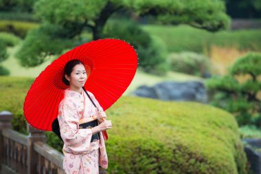 Genç Asyalı kız geleneksel Japon kimonosu ve kırmızı şemsiye giyiyor.