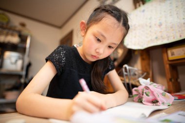 Küçük kız evde ders çalışıyor. 