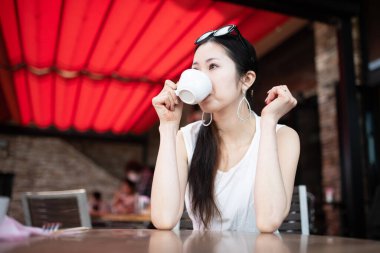 Kafede kahve içen Asyalı genç bir kadın.