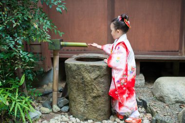 Japon bahçesinde kimono giyen bir kız oynuyor.