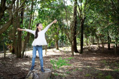 Çocuk ormanda kollarını açar.