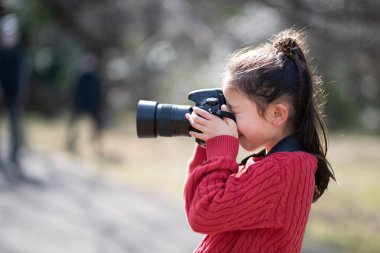 Tek lensli refleks kamerayla fotoğraf çeken bir kız.