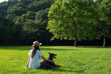 Doberman 'la birlikte çimlerde dinlenen kadın.