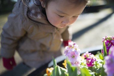 Bahçede çiçekleri olan küçük tatlı Asyalı kız.