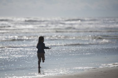 Gün doğumunda sahilde yürüyen kız.