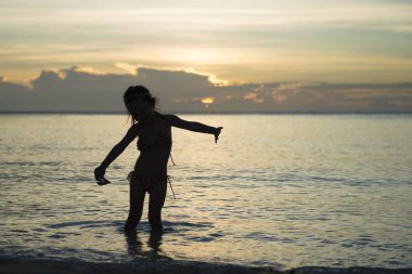 Gün batımında sahilde koşan bikinili tatlı Asyalı kız.