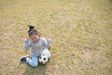 Genç kız futbol topuyla oynuyor. 