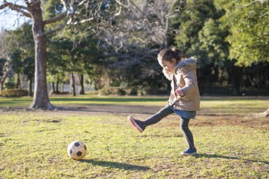 Kız parkta topla oynuyor.