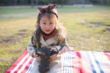 Küçük kız parkta kamerayla oynuyor.