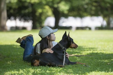 Kadın ağacın altında Doberman 'la rahatlıyor.