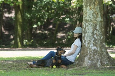 Kadın ağacın altında Doberman 'la rahatlıyor.