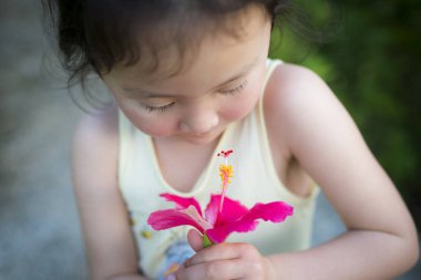 Küçük tatlı Asyalı kız elinde çiçek tutuyor.