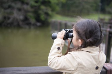 Doğada dürbünü olan sevimli Asyalı küçük kız.