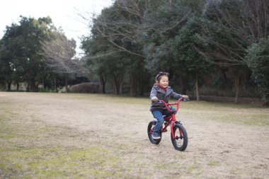 Ormanda bisiklet süren Asyalı bir çocuk.