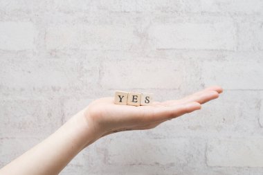 Gri ahşap arka planda bir kadının el ele tutuşması evet diyor.. 