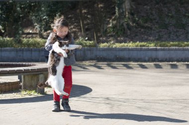 Parkta kedisi olan sevimli Asyalı kız. 