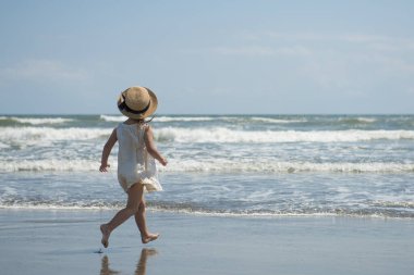 Küçük tatlı Asyalı kız sahilde yürüyor.