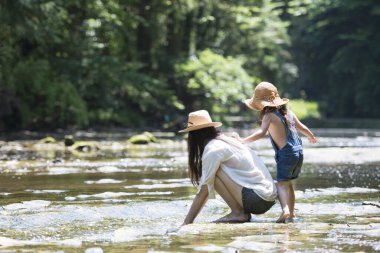 Anne ve kızı nehirde oynuyorlar.