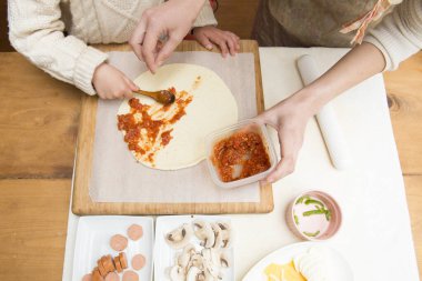 Anne ve kızı pizza yapıyor.