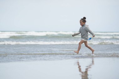Güzel Asyalı kız sahilde koşuyor..