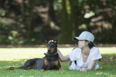 Kadın ağacın altında Doberman 'la rahatlıyor.