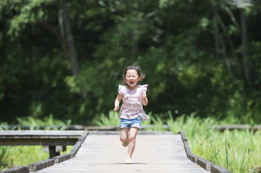 Ormanda koşan Asyalı küçük çocuk.