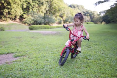 Parkta bisiklete binen küçük çocuk.
