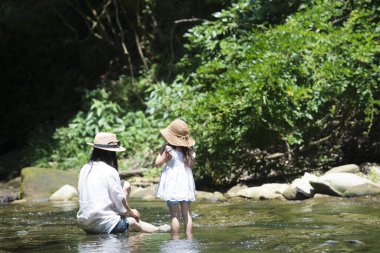 Anne ve kızı nehirde oynuyorlar.
