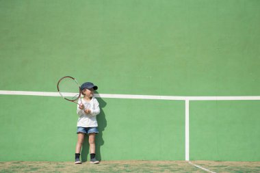 Sahada tenis oynayan sevimli Asyalı kız.