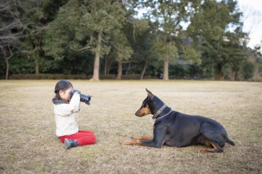 Parkta bir köpeğin fotoğrafını çeken bir kız.