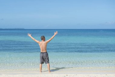 Sahilde elini kaldıran bir adam.