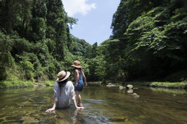 Anne ve kızı nehirde oynuyorlar.