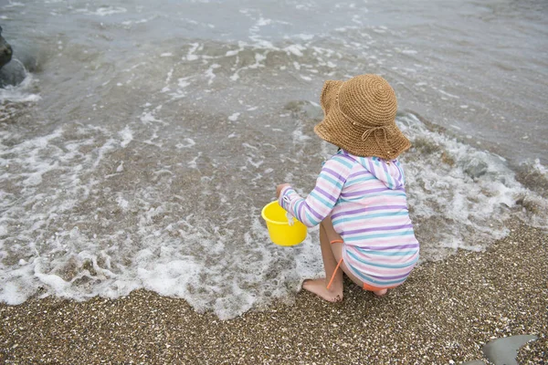 little girl with bucket playing  in the water