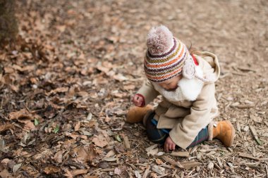 Bir çocuk sonbahar ormanında oynuyor.