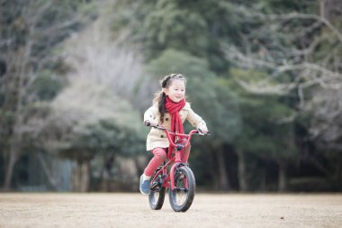 Parkta bisiklete binen küçük kız 