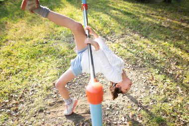 Sonbahar parkında yatay barda oynayan kız