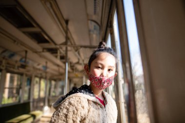 Trende yüz maskesi takan Asyalı kız. seyahat ve güvenlik kavramı.